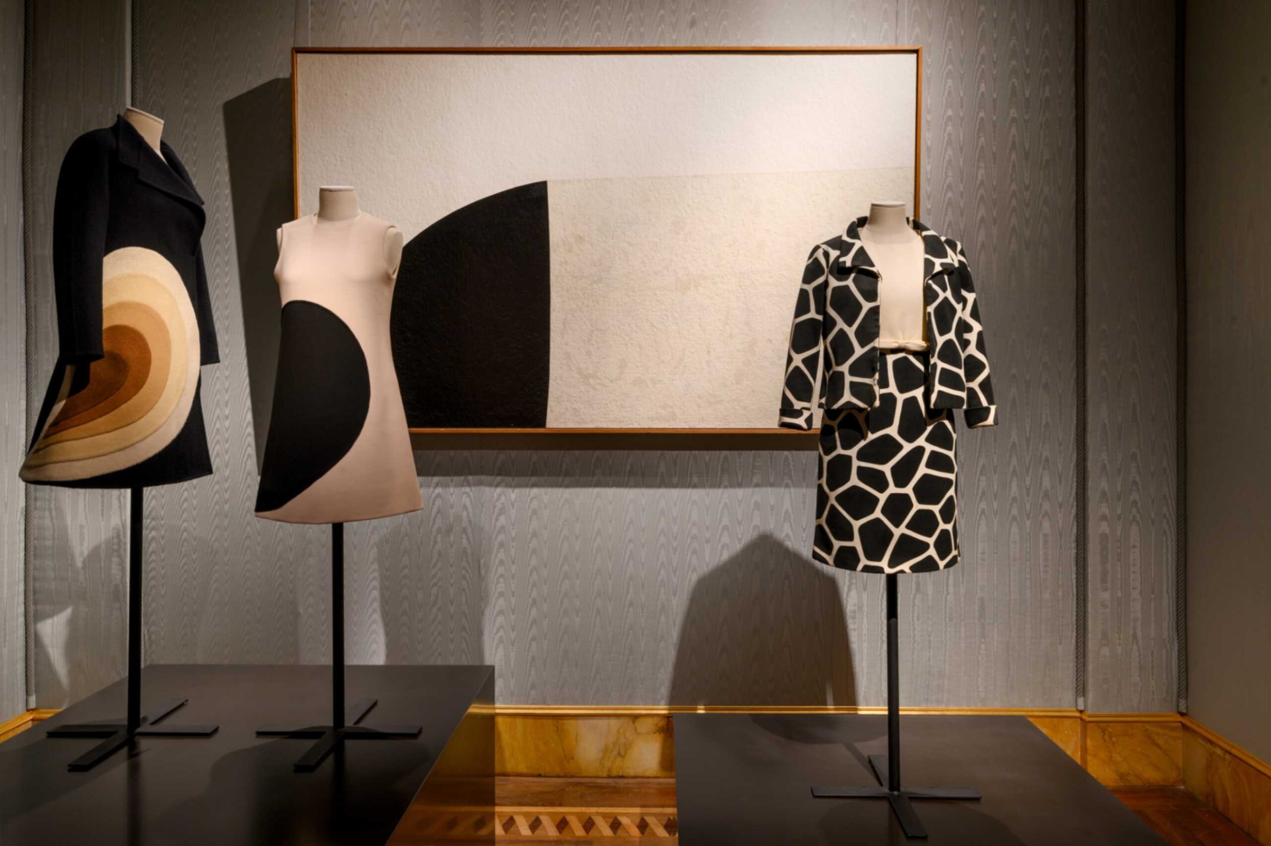 SALA 14 Abito e cappotto in panno di lana con intarsi di Federico Forquet (1968) e tailleur in crespo di lana bianco e nero di Valentino (1966). Sulla parete l’opera Bianco e nero di Alberto Burri (1969)