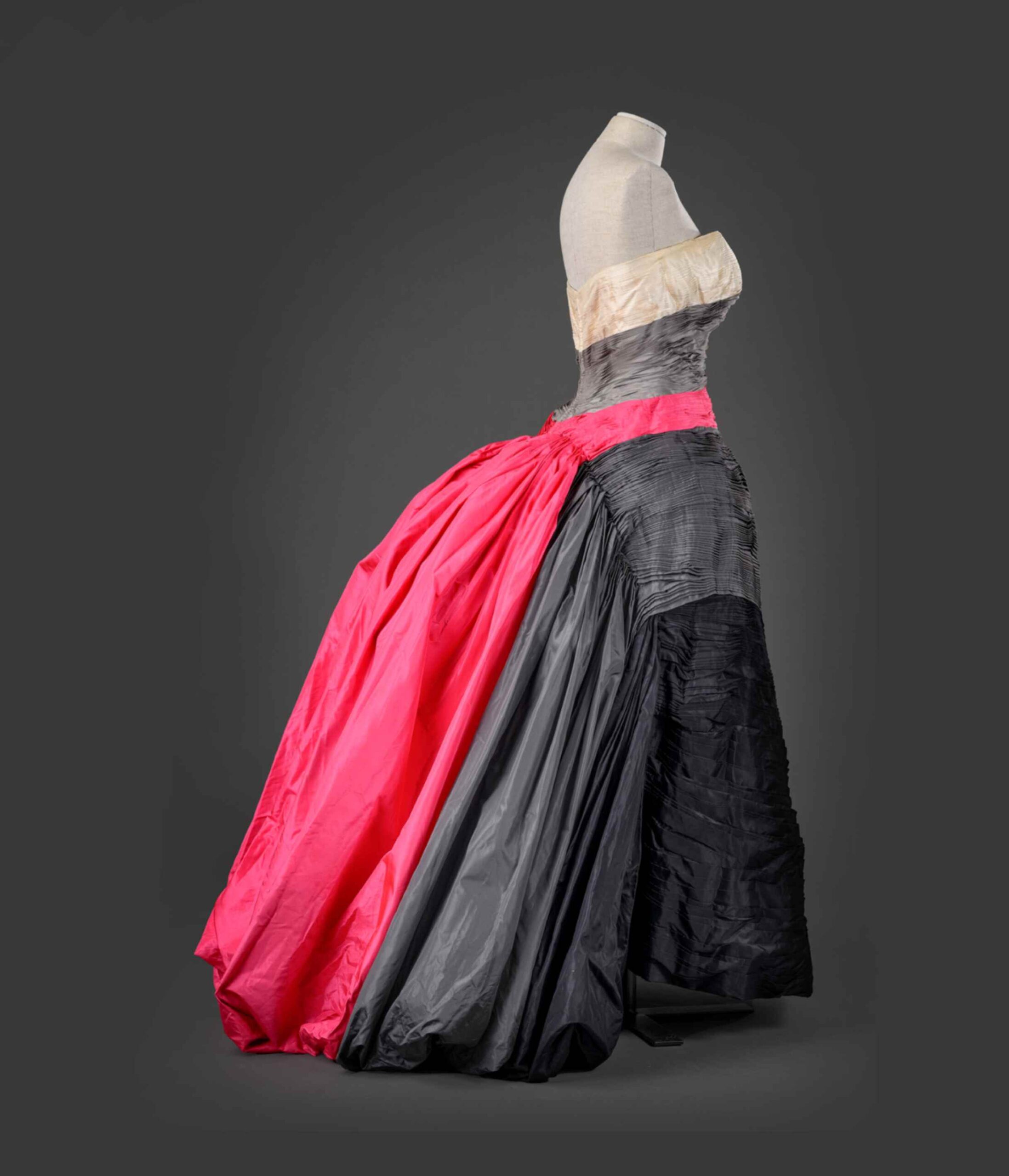EMILIO FEDERICO SCHUBERTH, ROMA Napoli 1904 – Roma 1972 ABITO FEMMINILE 1955 circa Etichetta: “Emilio Schuberth-Roma” Abito da gran sera in tafettas di seta pieghettata avorio, grigio chiaro, fucsia, grigio scuro e nero. Scollatura a cuore con corpetto interamente steccato, pieghe libere dal fianco che formano strascico con ogni colore del taffetas. Sottogonne in crine nero e rosso. Dono di Gaia Pace. Appartenuto a Loretta De Angelis Pace.